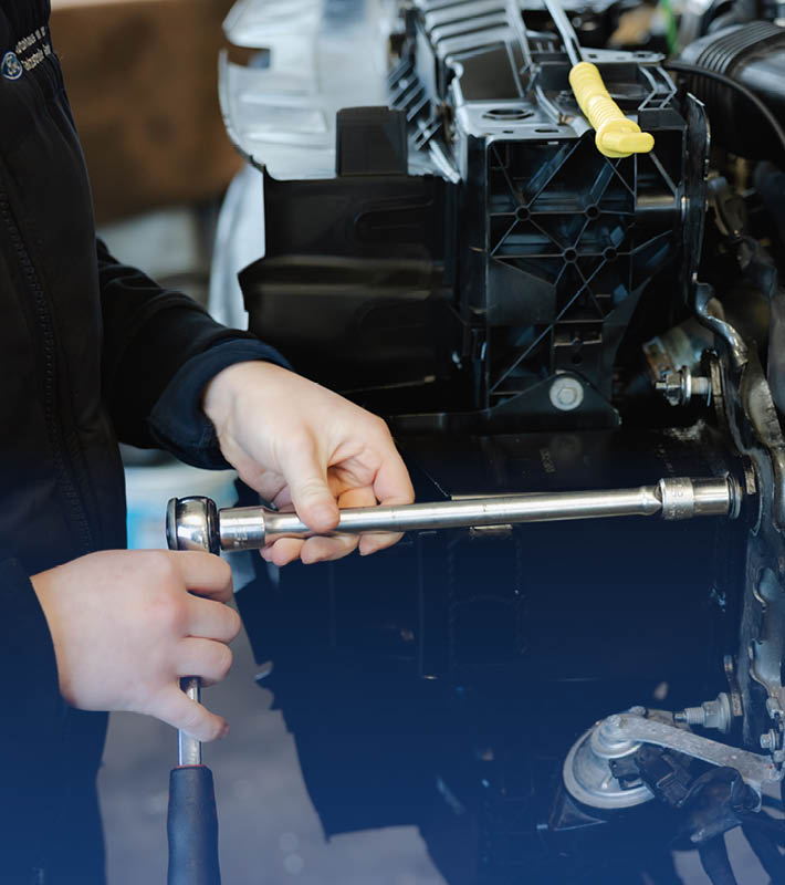 Mitarbeiter schraubt etwas am Auto